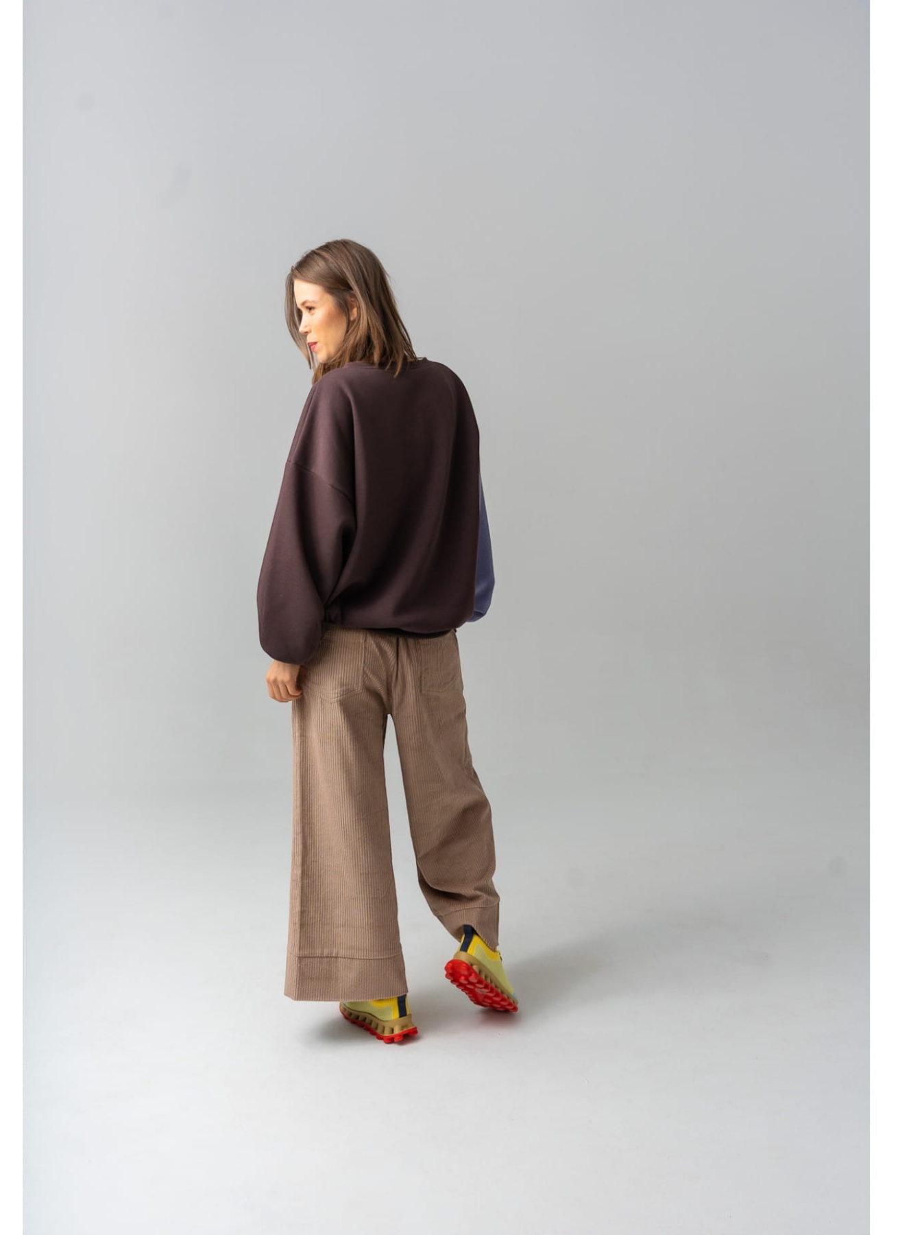 Modelka w brązowych kulotach COFFEE z bawełnianego sztruksu, z szerokimi nogawkami i gumką w pasie.