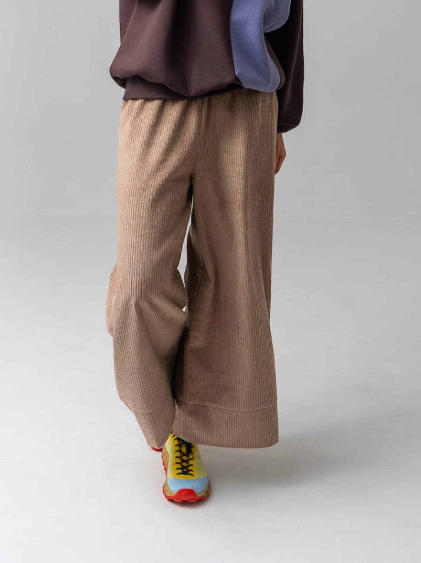 Modelka w brązowych kulotach COFFEE z bawełnianego sztruksu, z szerokimi nogawkami i gumką w pasie.