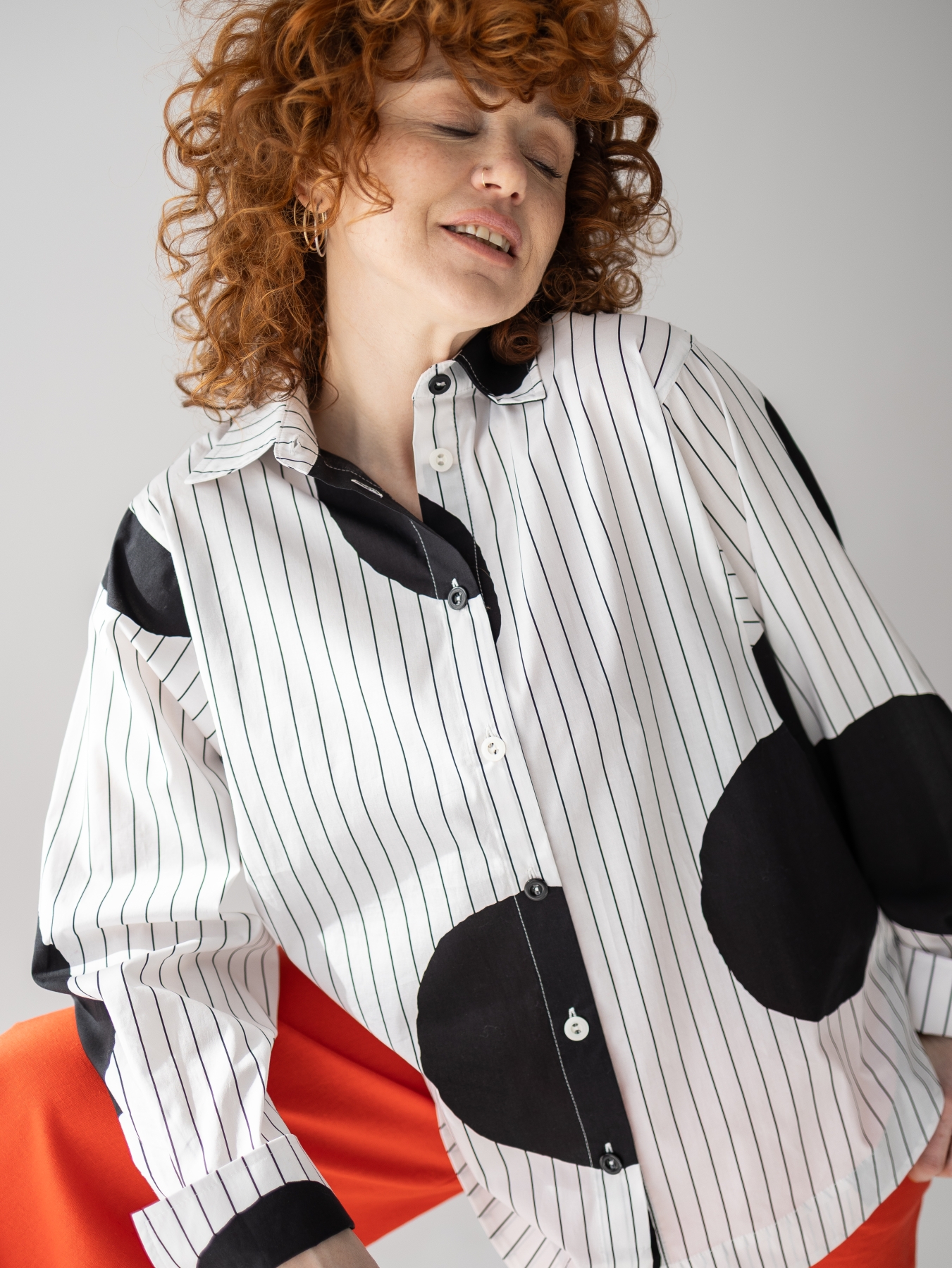 Koszula z lekkiej tkaniny w biało-czarnym kolorze, o luźnym kroju, z kołnierzykiem, mankietami oraz kontrastowym wzorem w paski i grochy.