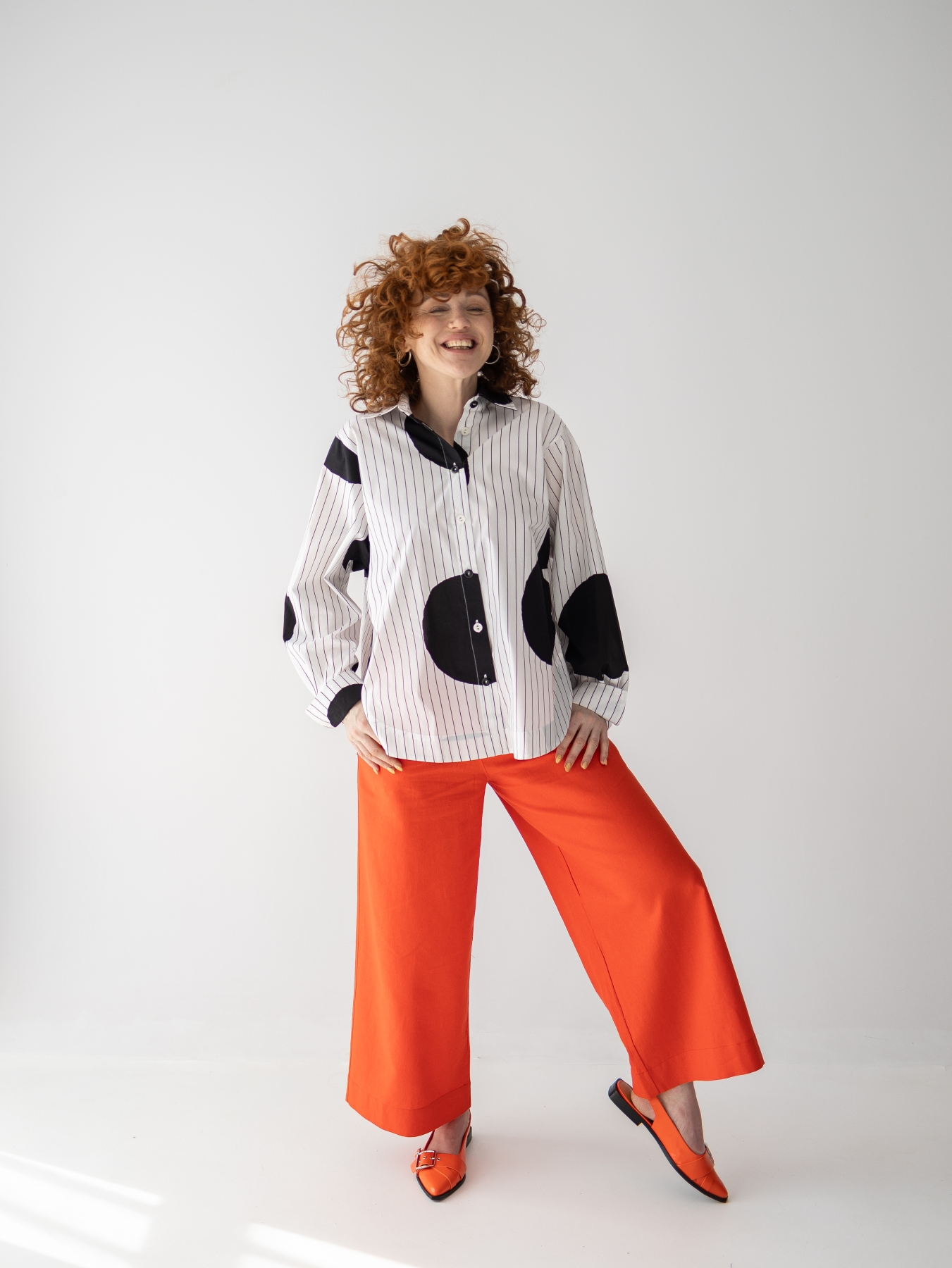 Koszula z lekkiej tkaniny w biało-czarnym kolorze, o luźnym kroju, z kołnierzykiem, mankietami oraz kontrastowym wzorem w paski i grochy.