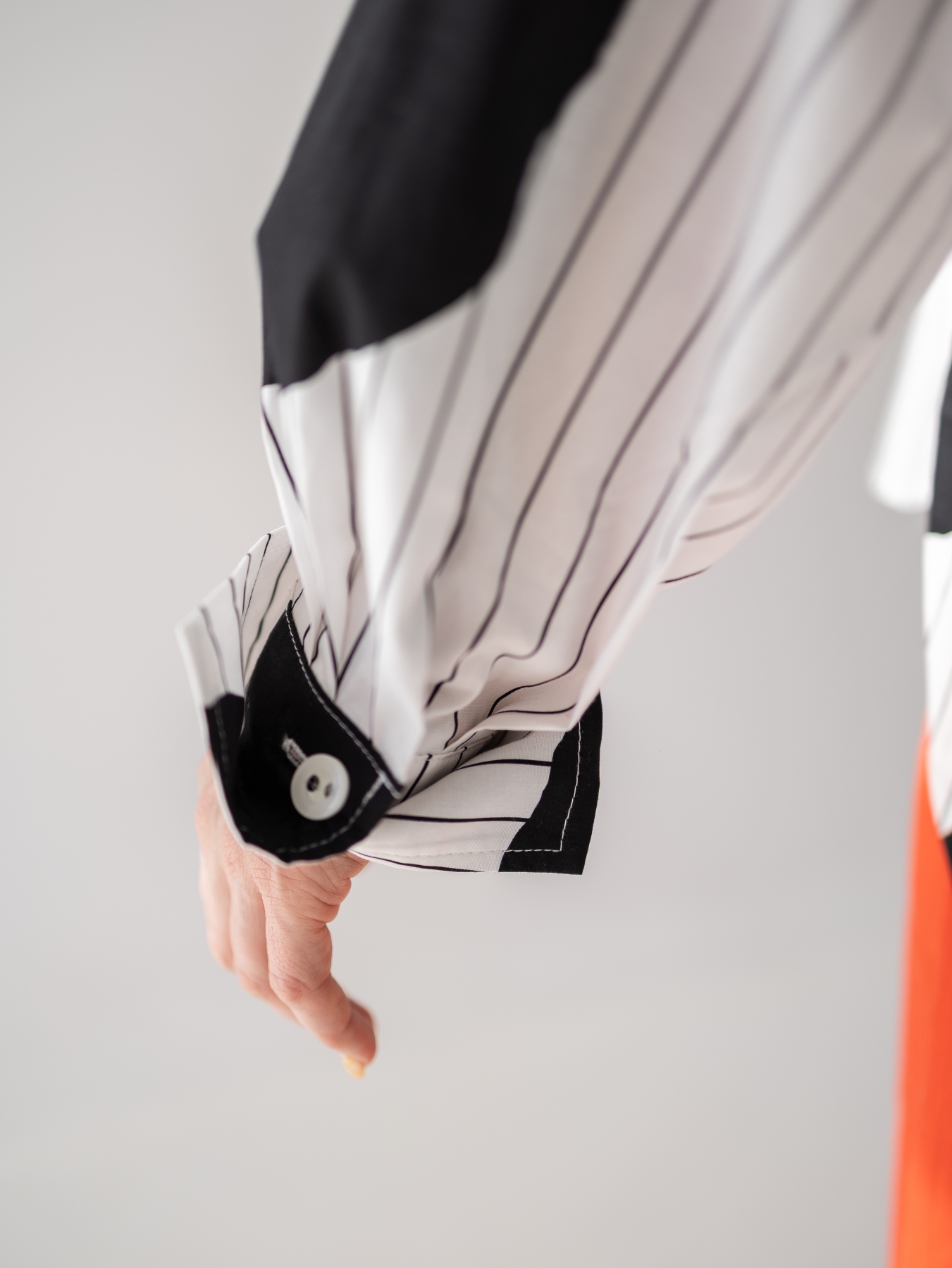 Koszula z lekkiej tkaniny w biało-czarnym kolorze, o luźnym kroju, z kołnierzykiem, mankietami oraz kontrastowym wzorem w paski i grochy.