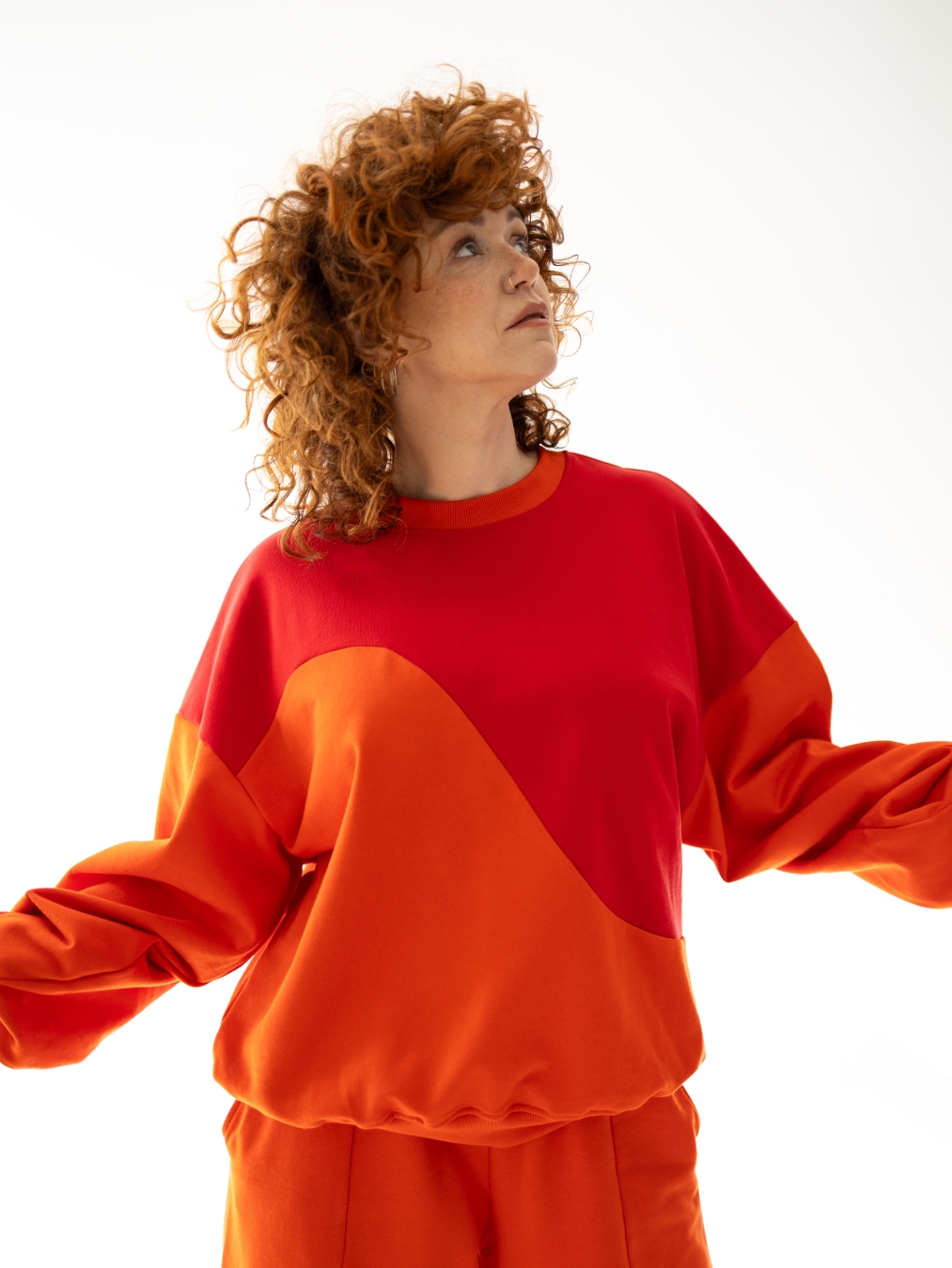Bluza Terra Sun oversize w kolorze czerwono-pomarańczowym z asymetrycznym, geometrycznym cięciem na przodzie.