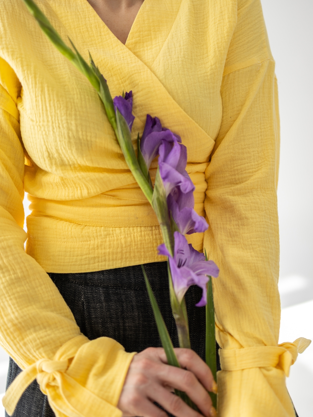 Żółta bluzka Violetta o kopertowym kroju z wiązaniem w talii i ozdobnymi wiązaniami przy rękawach.