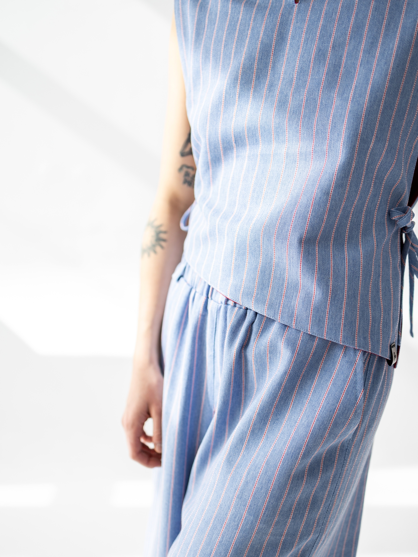 Dwustronna kamizelka Lucia bez rękawów, czerwona z jednej strony i w jasnoniebieski prążek z drugiej.