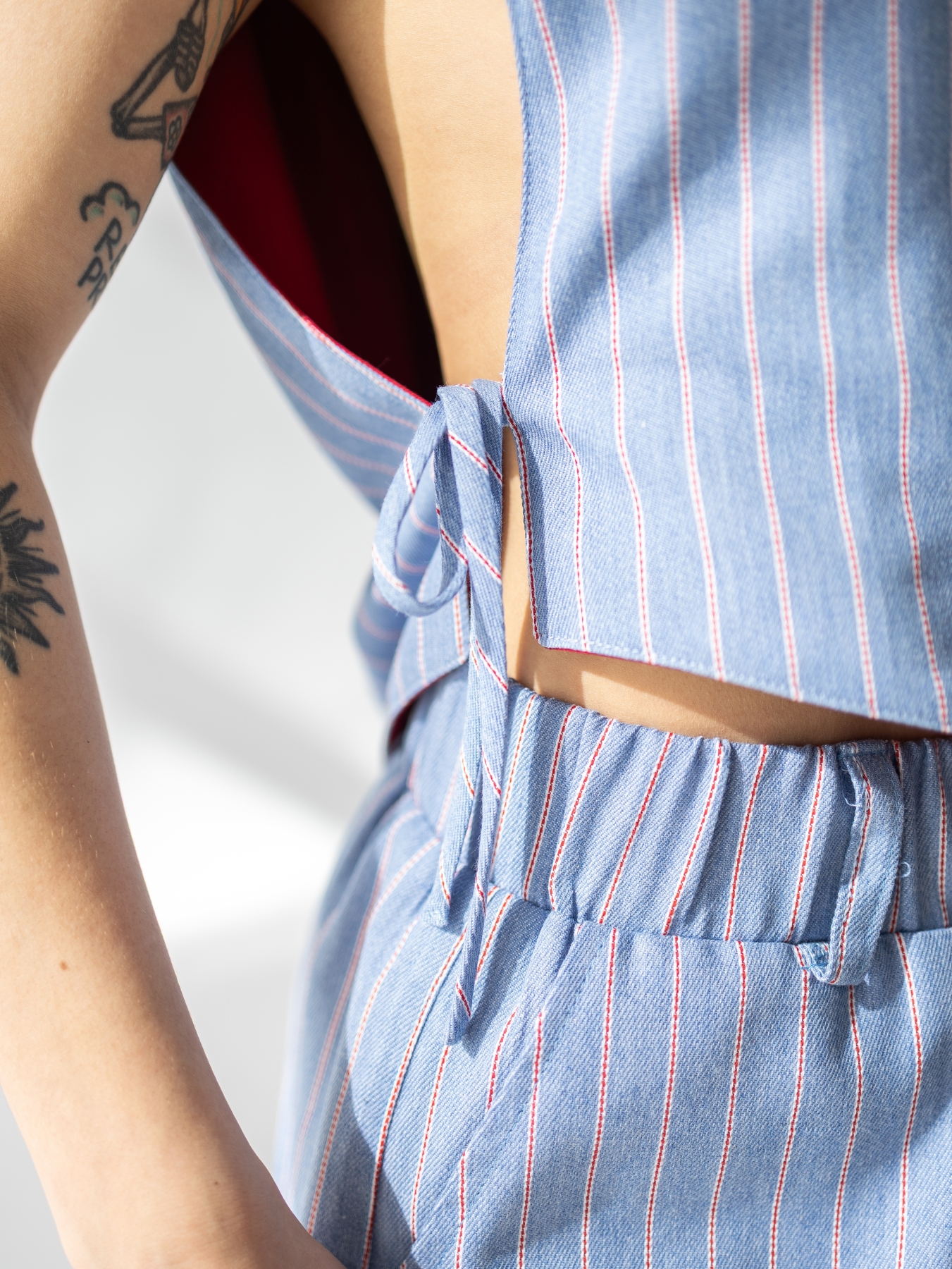 Dwustronna kamizelka Lucia bez rękawów, czerwona z jednej strony i w jasnoniebieski prążek z drugiej.