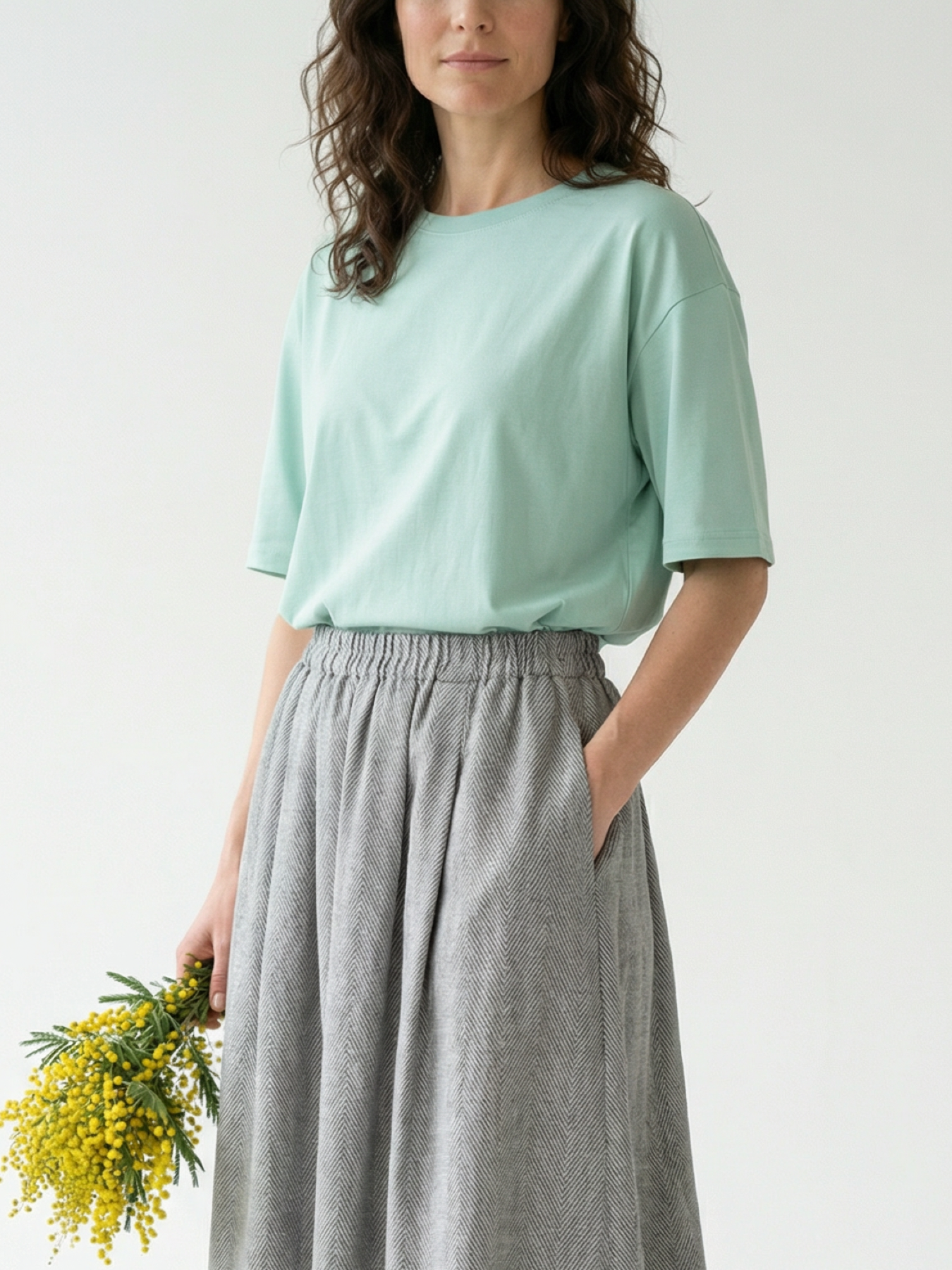 Modelka w miętowej BLUZCE MINT o swobodnym, lekko oversize’owym fasonie i krótkim rękawie.
