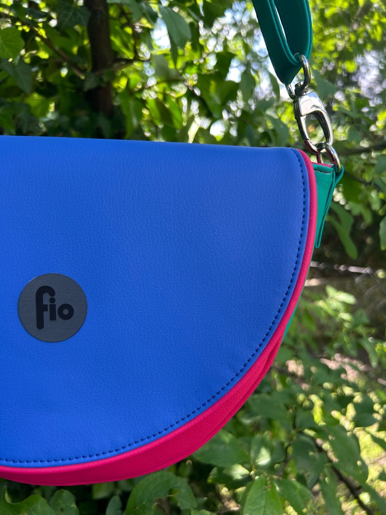 Nerka półokrągła zawieszona na zielonym pasku, z niebieską klapką i różowym przodem.